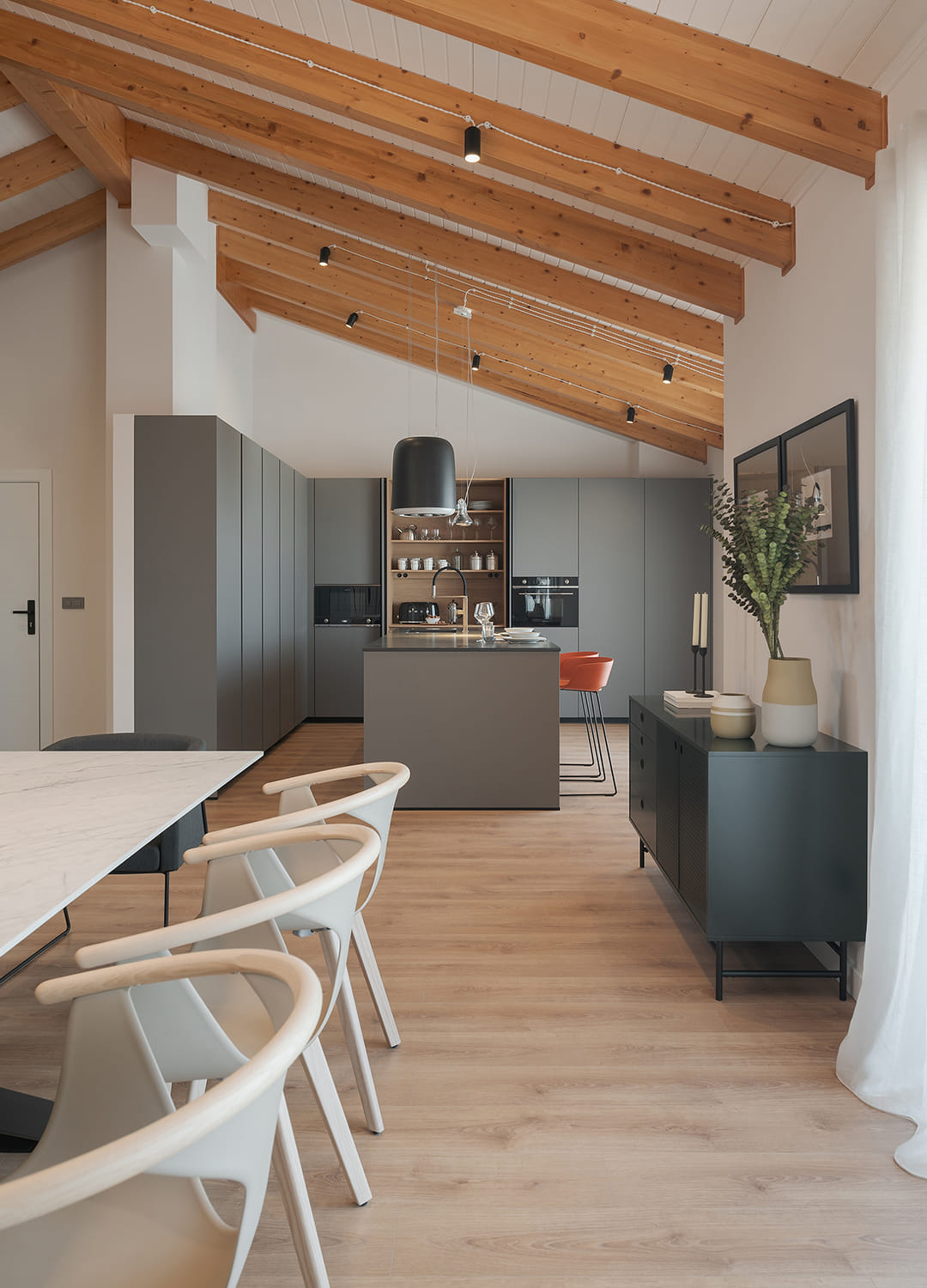 Cocina gris con isla abierta al salón y armarios escamoteables abiertos.