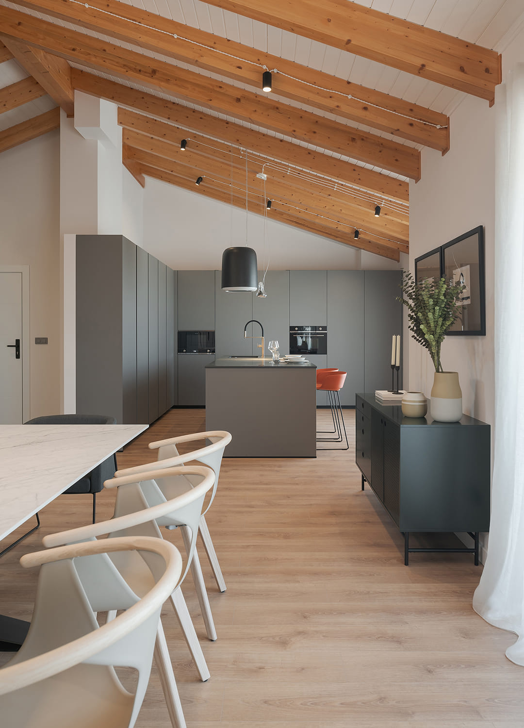 Cocina gris con isla de Santos abierta al salón con muebles escamoteables.