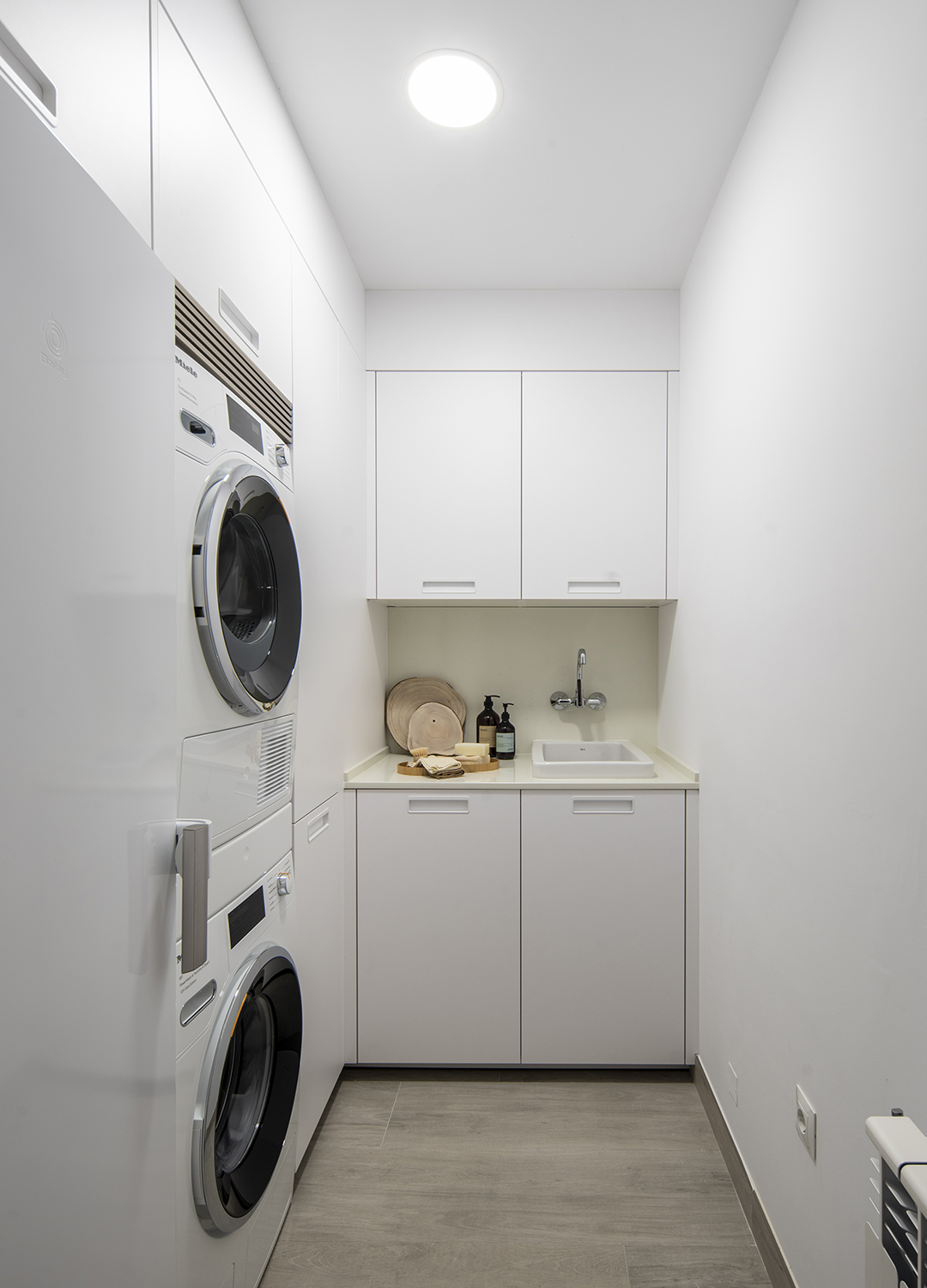 Zona de lavandería equipada con muebles ELEA Blanco Innsbruck diseñados por Cocinas Santos.