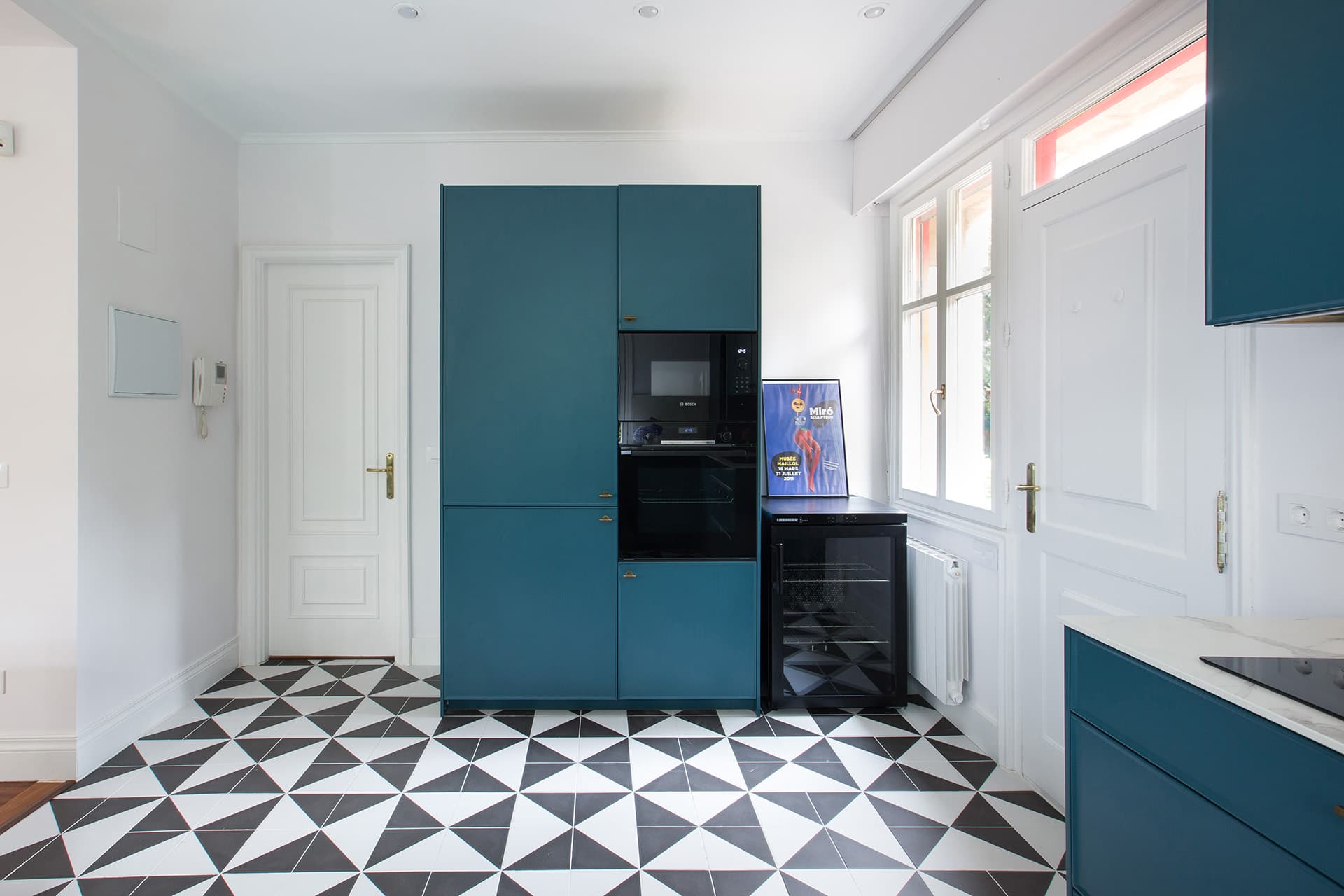Tall units with integrated electrical appliances in a blue Santos kitchen.