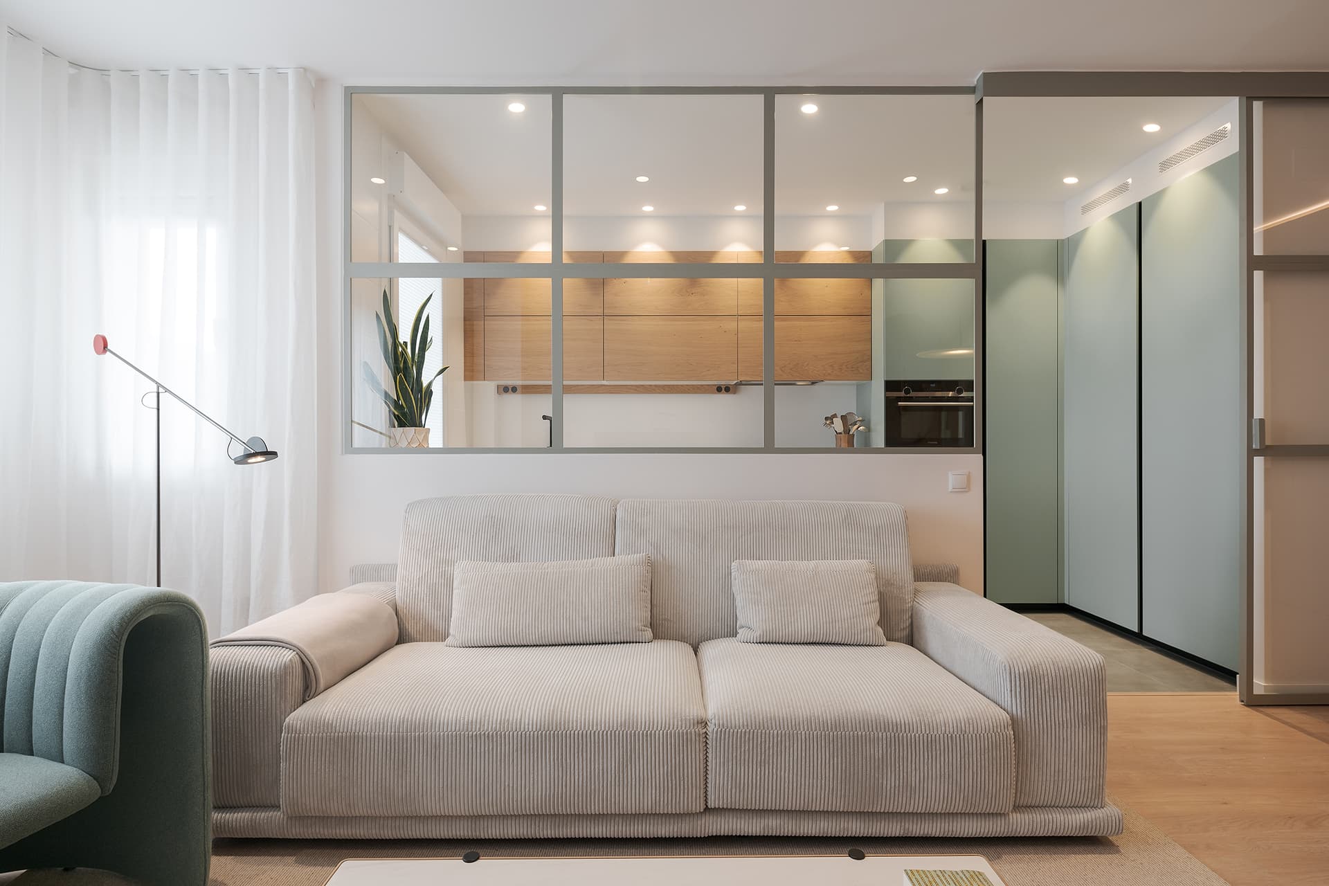 Green kitchen open to the lounge designed by Santos Kitchens.