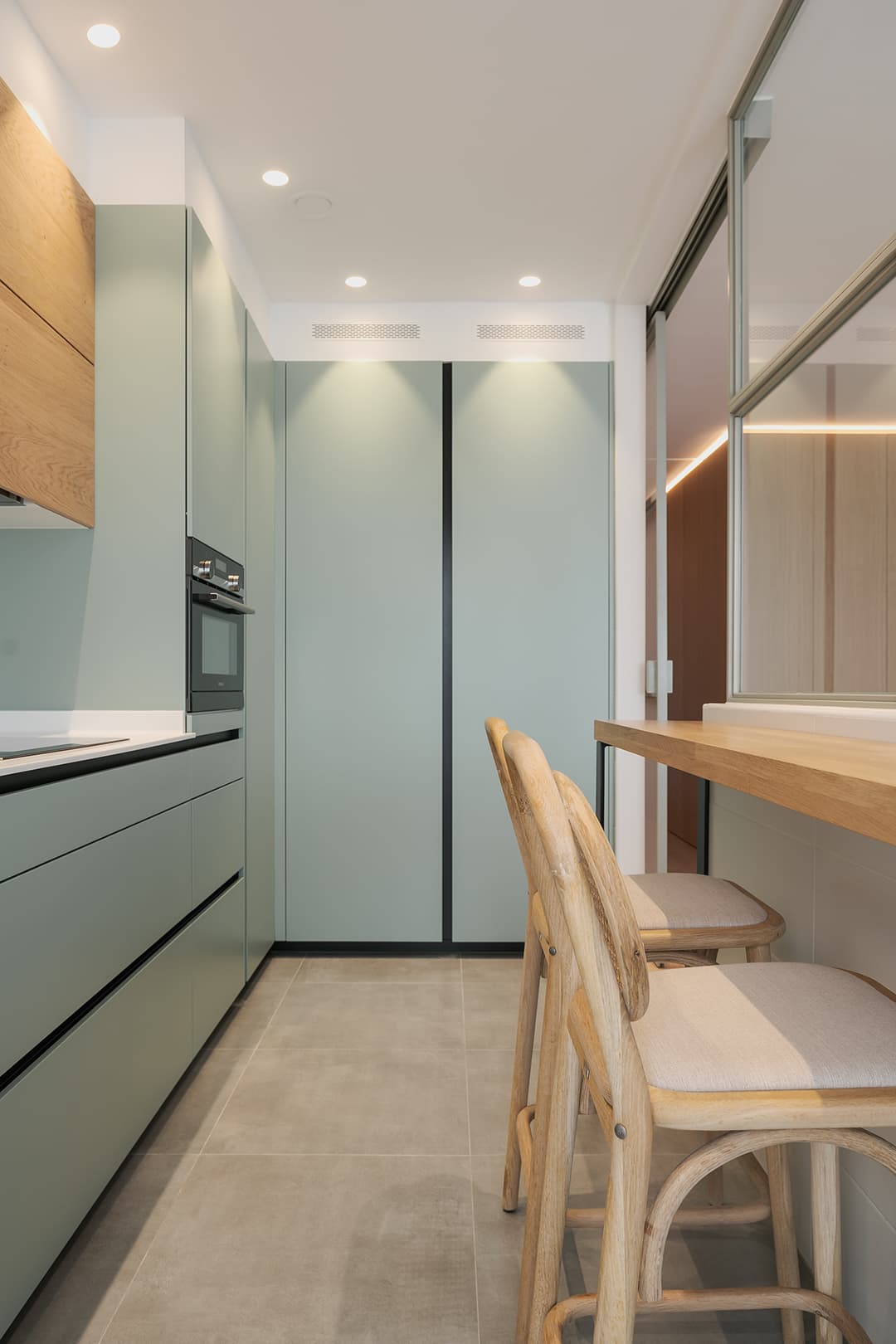 L-shaped green kitchen with wood counter.