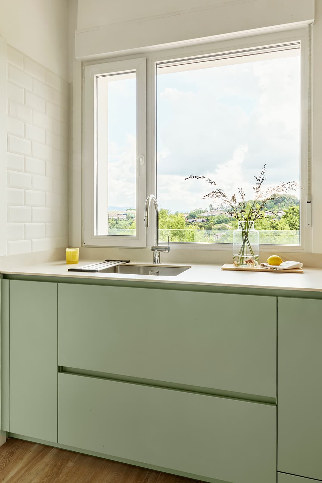 Sage Green kitchen with white worktop and sink next to the window designed by Santos Kitchens.