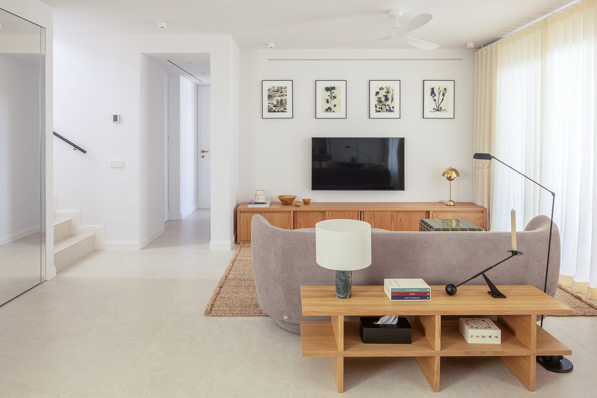 Salón en una vivienda que incluye una cocina blanca y madera de Santos.