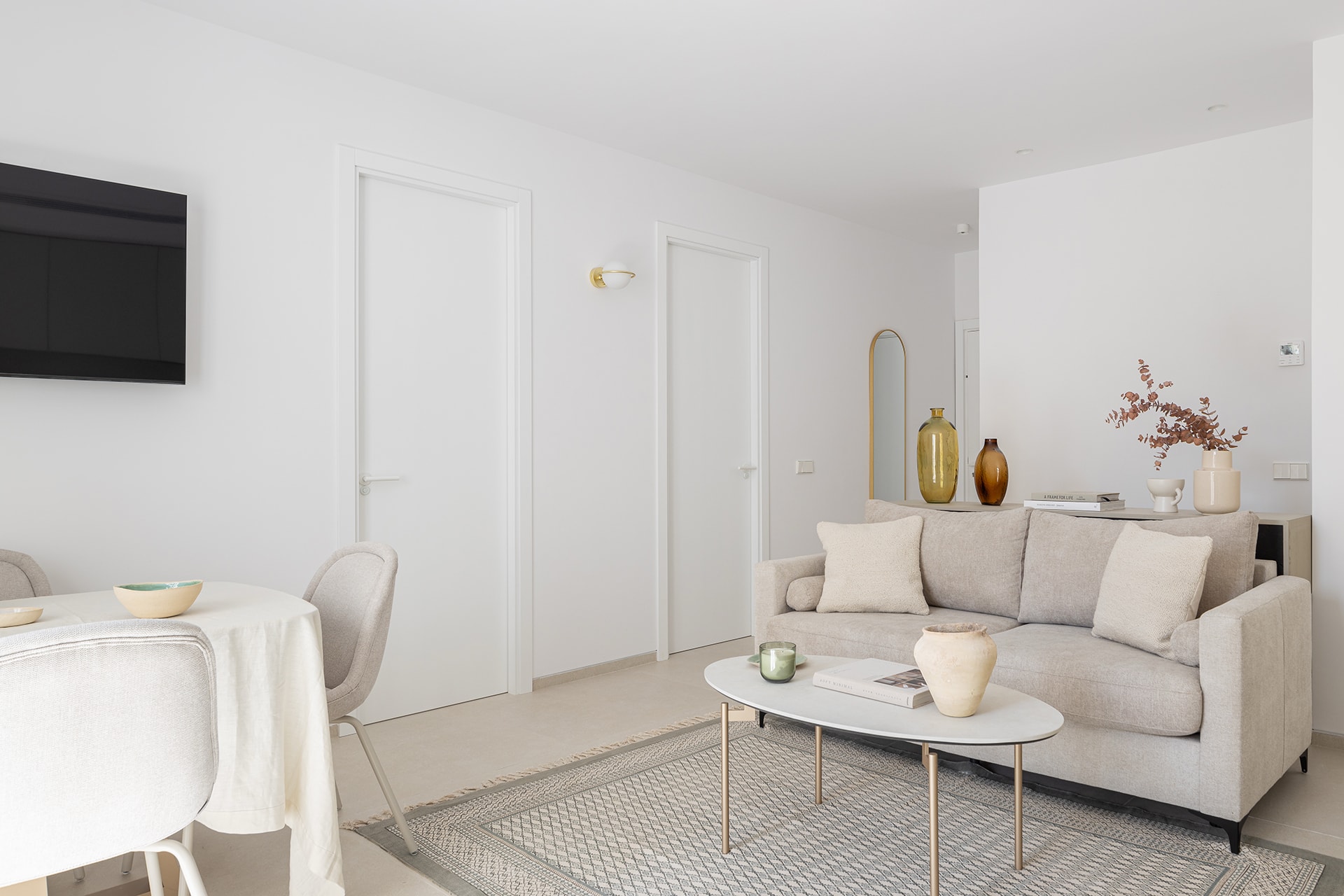 Vista del salón en una vivienda con una cocina blanca diseñada por Santos.