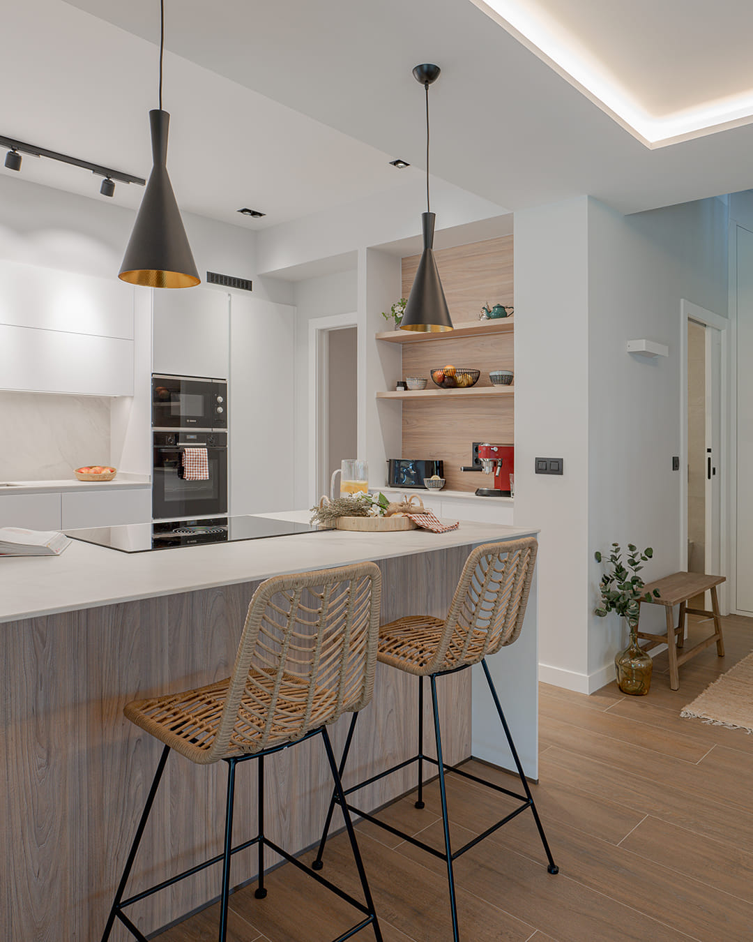Cocina blanca con península y desayunador en un proyecto de Cocinas Santos.