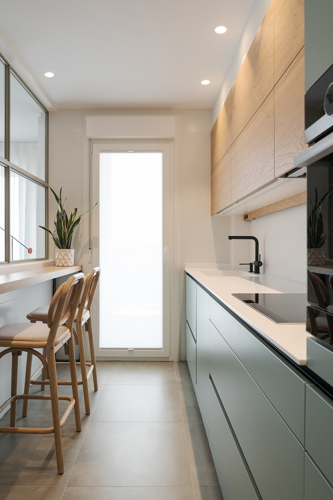 Smalle keuken in de kleur groen met houten afwerkingen.