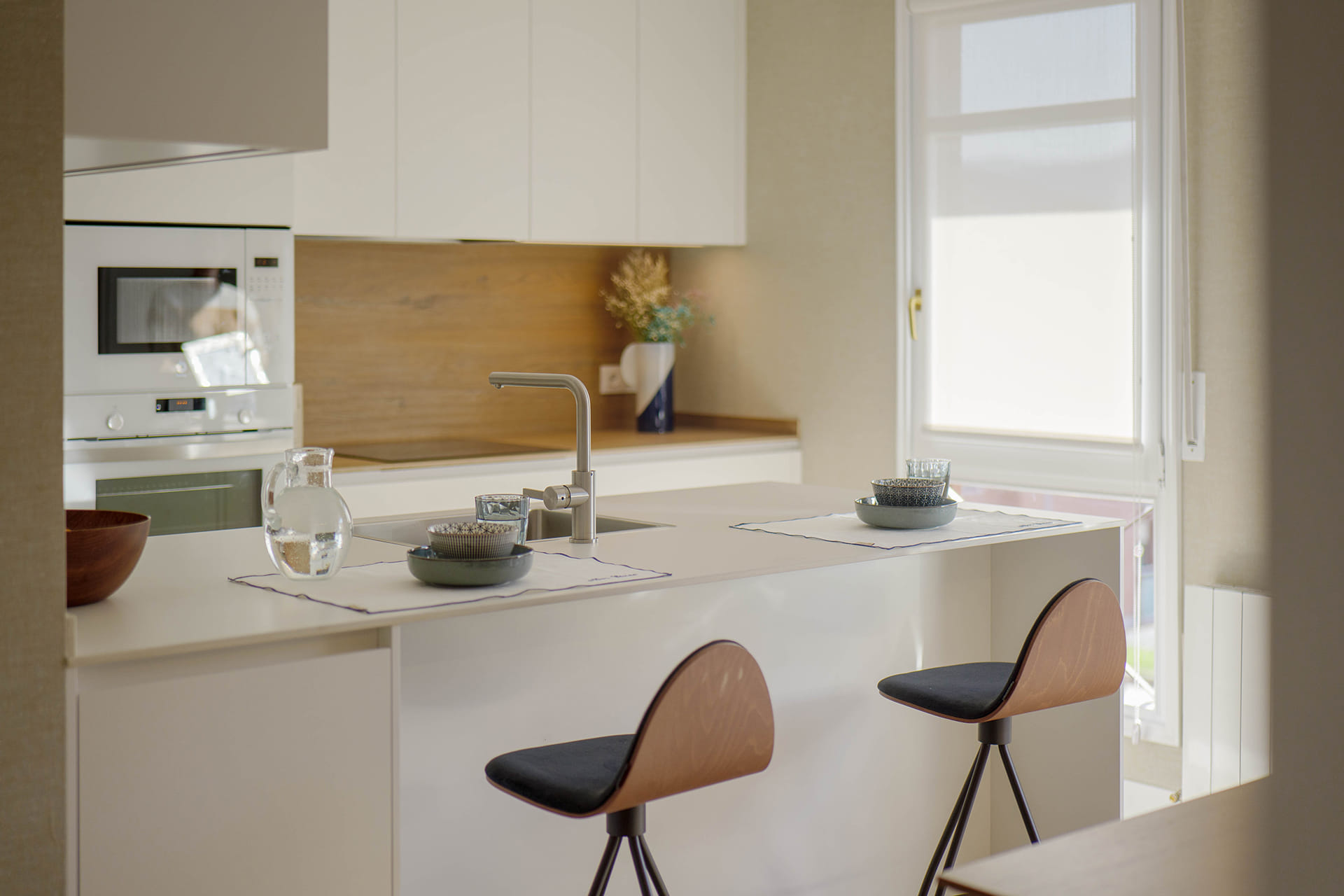 Cocina blanca en L con península diseñada por Cocinas Santos.