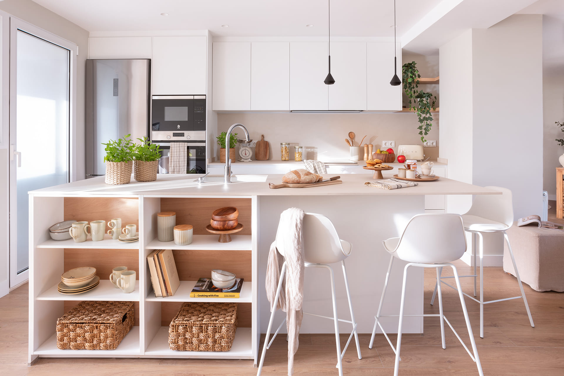 Cocina blanca con isla abierta al salón en un proyecto de Santos y Majo Flores.