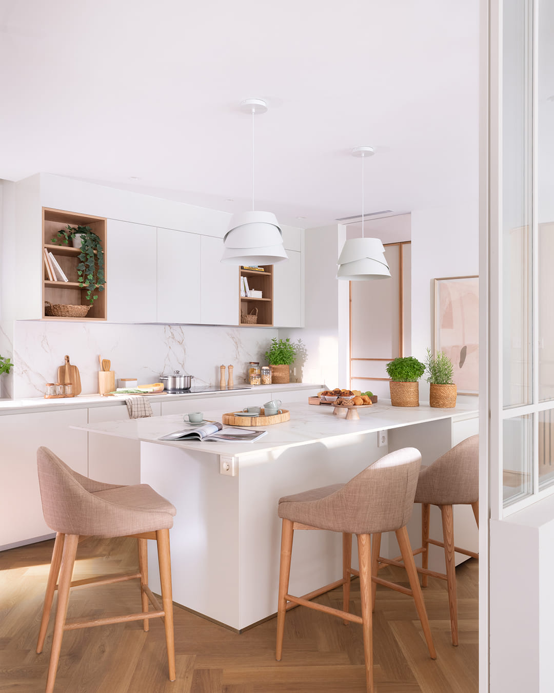 Isla de cocina blanca con lámparas de iluminación suspendida.
