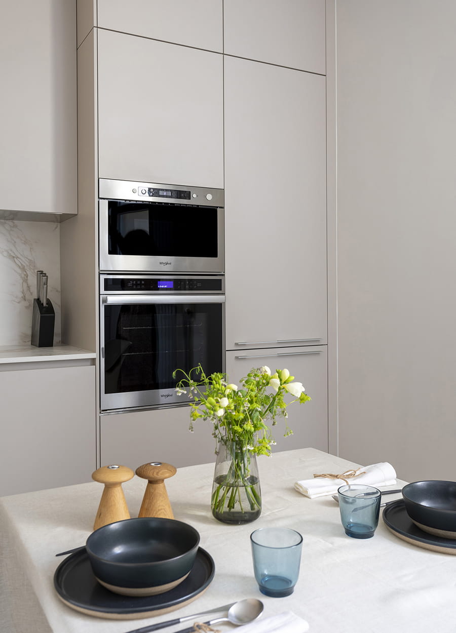 Zona para desayunos y armarios en columna con electrodomésticos integrados en una cocina Cashmere de Santos.