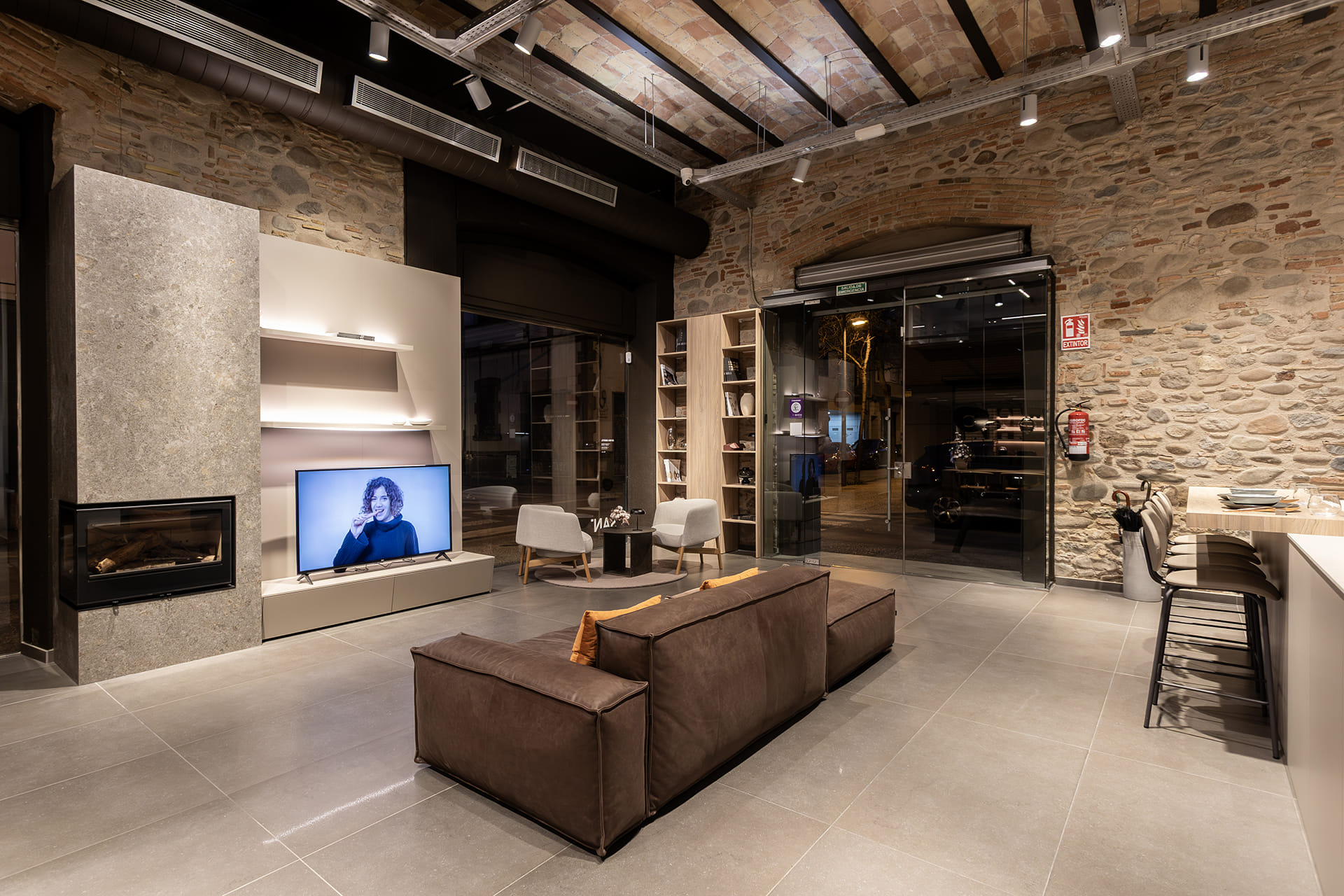 Zona de estar con librería al fondo en la tienda de cocinas Santos en Girona.
