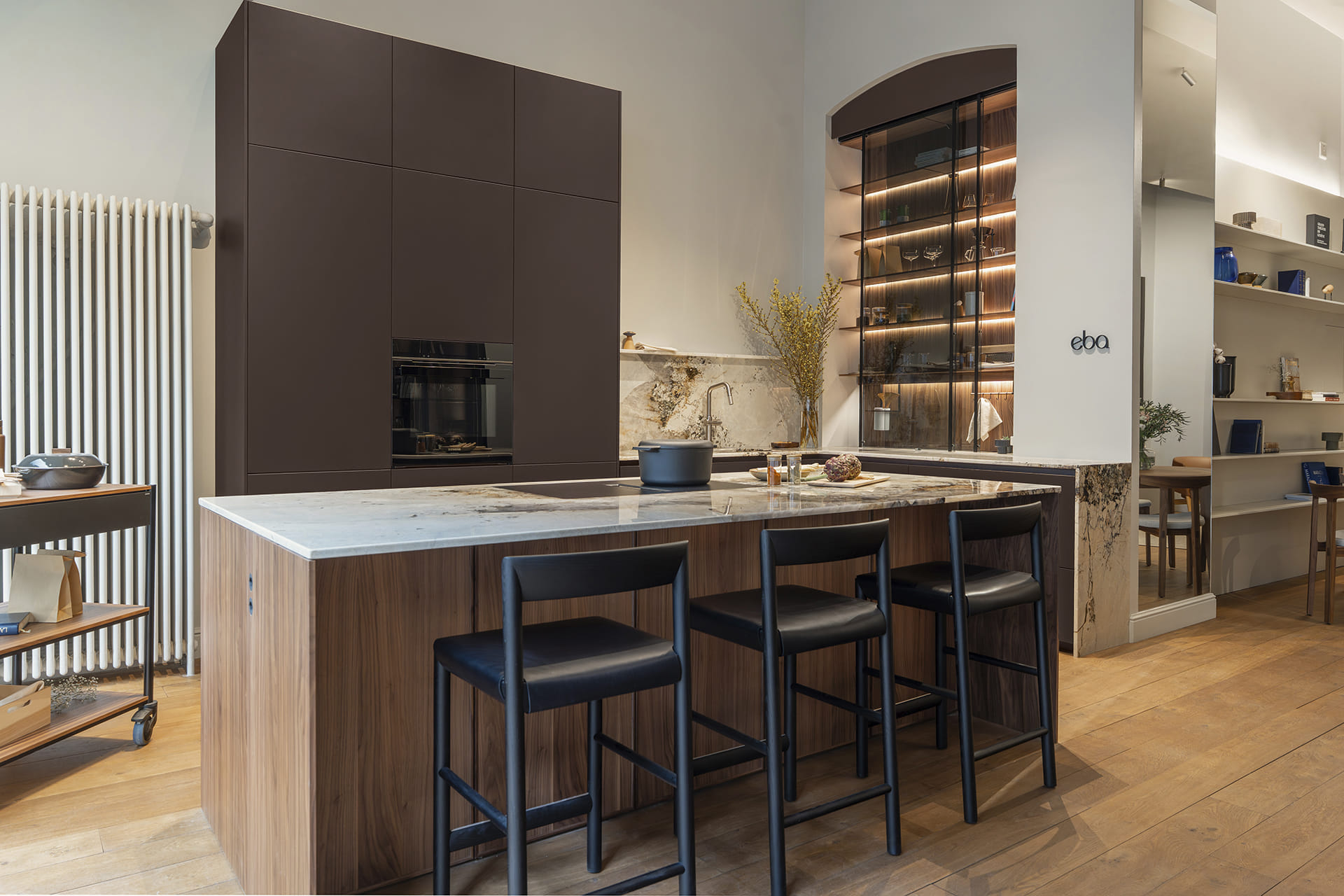 Vista de cocina marrón oscuro con isla en la tienda exclusiva eba Genève.