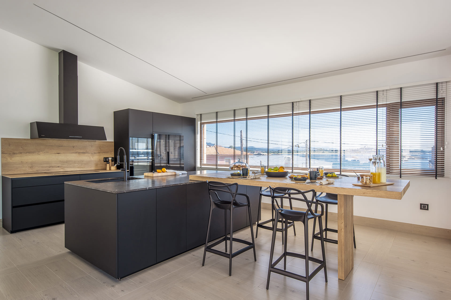 Cocina negra con acabados en madera y mesado de Santos.