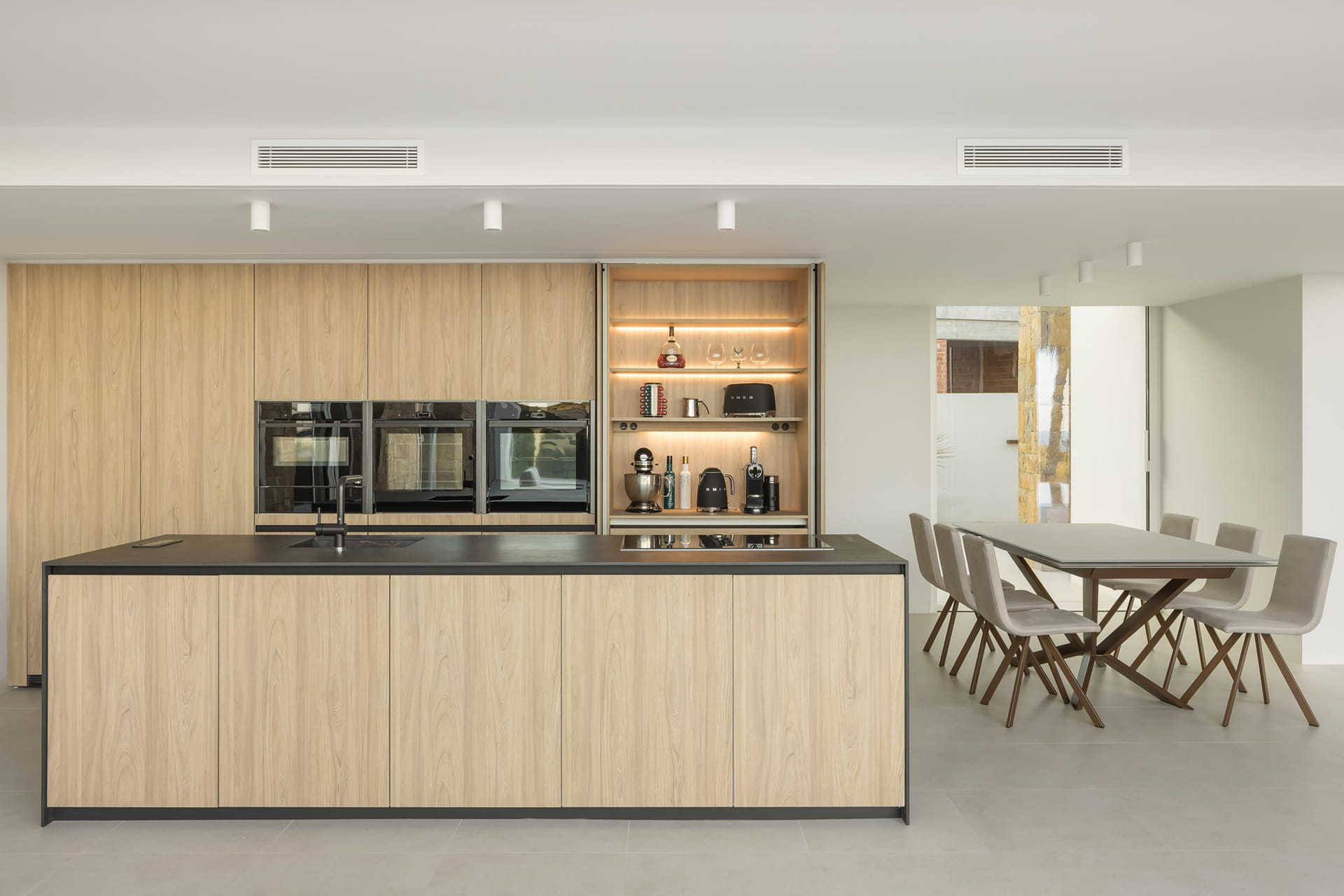 Cocina negra y madera abierta al comedor en un proyecto de Cocinas Santos.