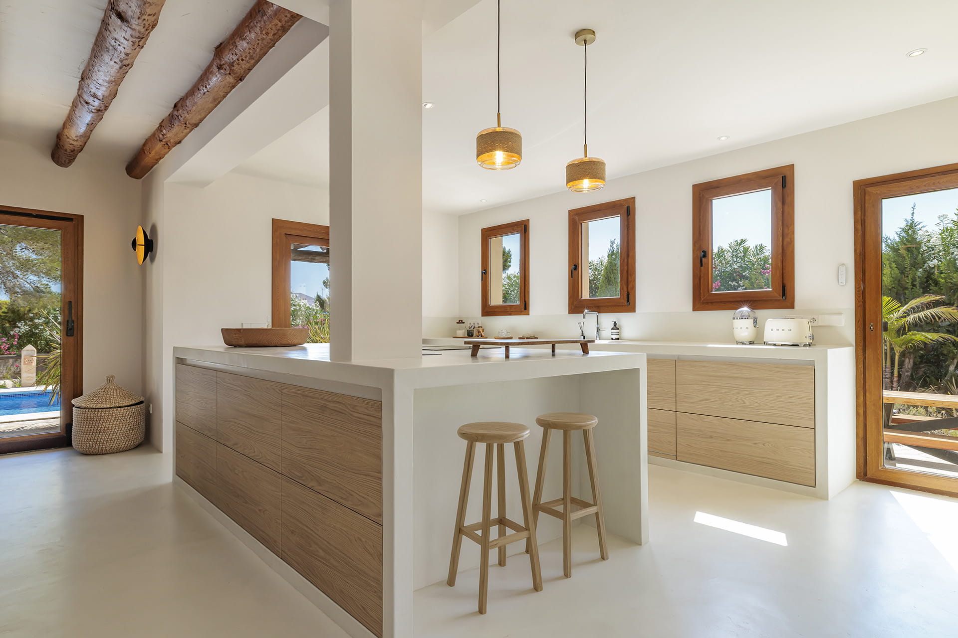 Cocina Santos con isla y taburetes abierta a la zona exterior.