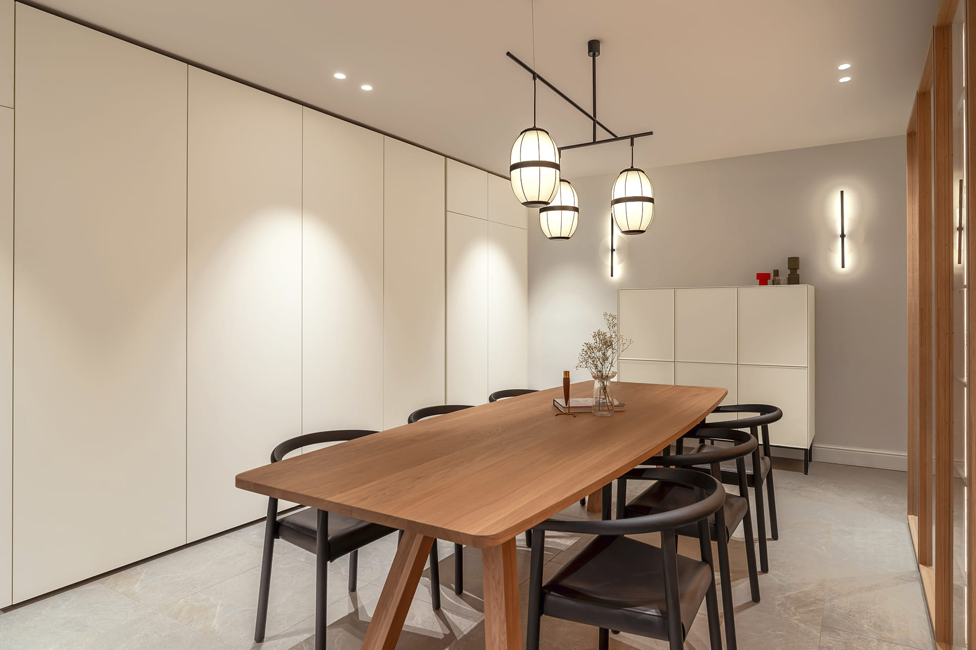 Zona de comedor con armarios de puertas escamoteables blancos en el showroom de Cocinas Santos en Suiza.