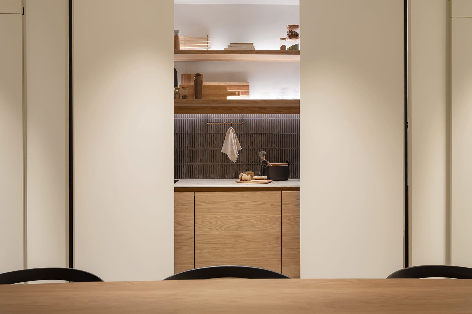 Puertas escamoteables dobles que ocultan una cocina lineal en el showroom de Cocinas Santos en Suiza.