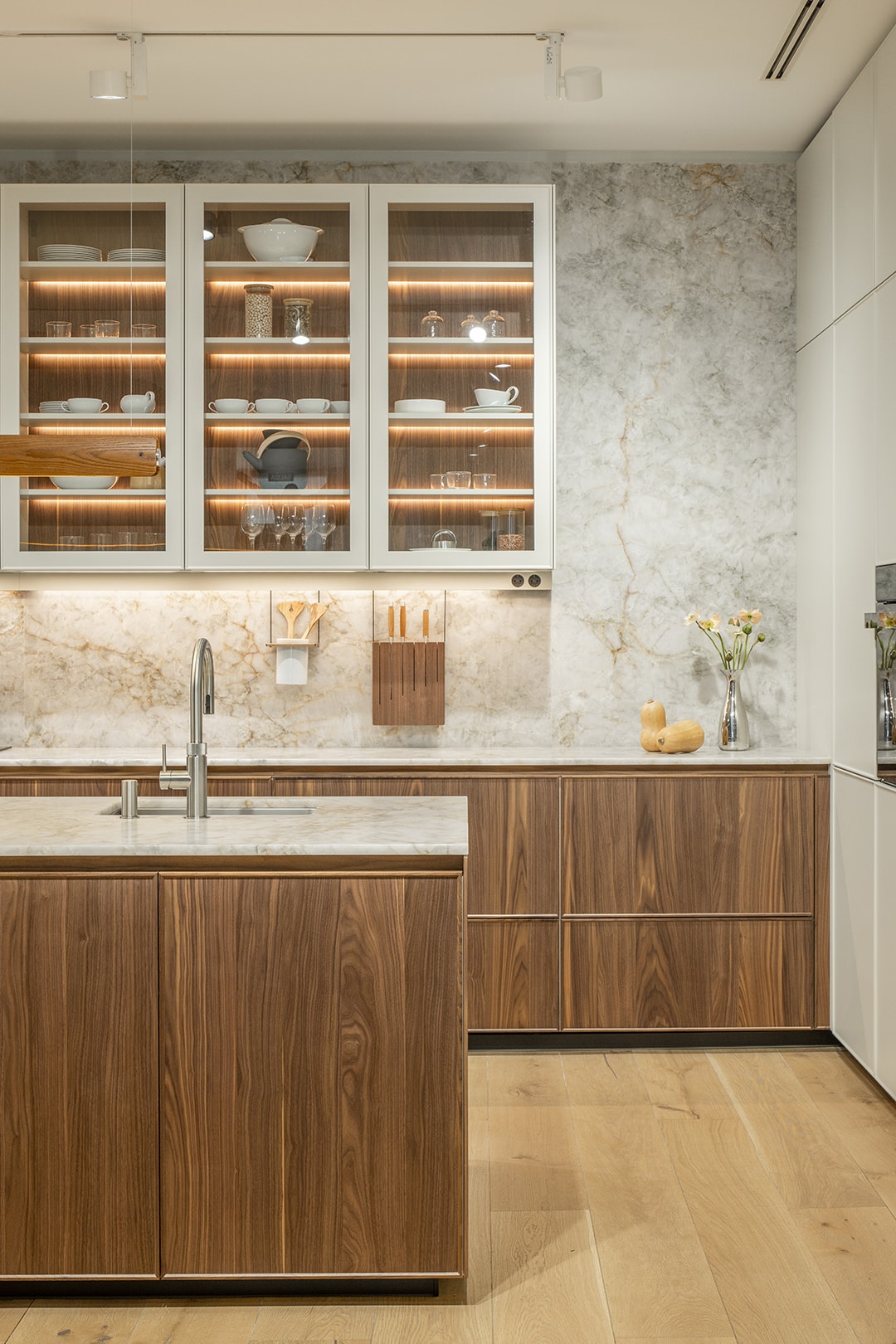 Cocina blanca con isla y acabados en madera en la nueva exposición de Santiago Interiores.
