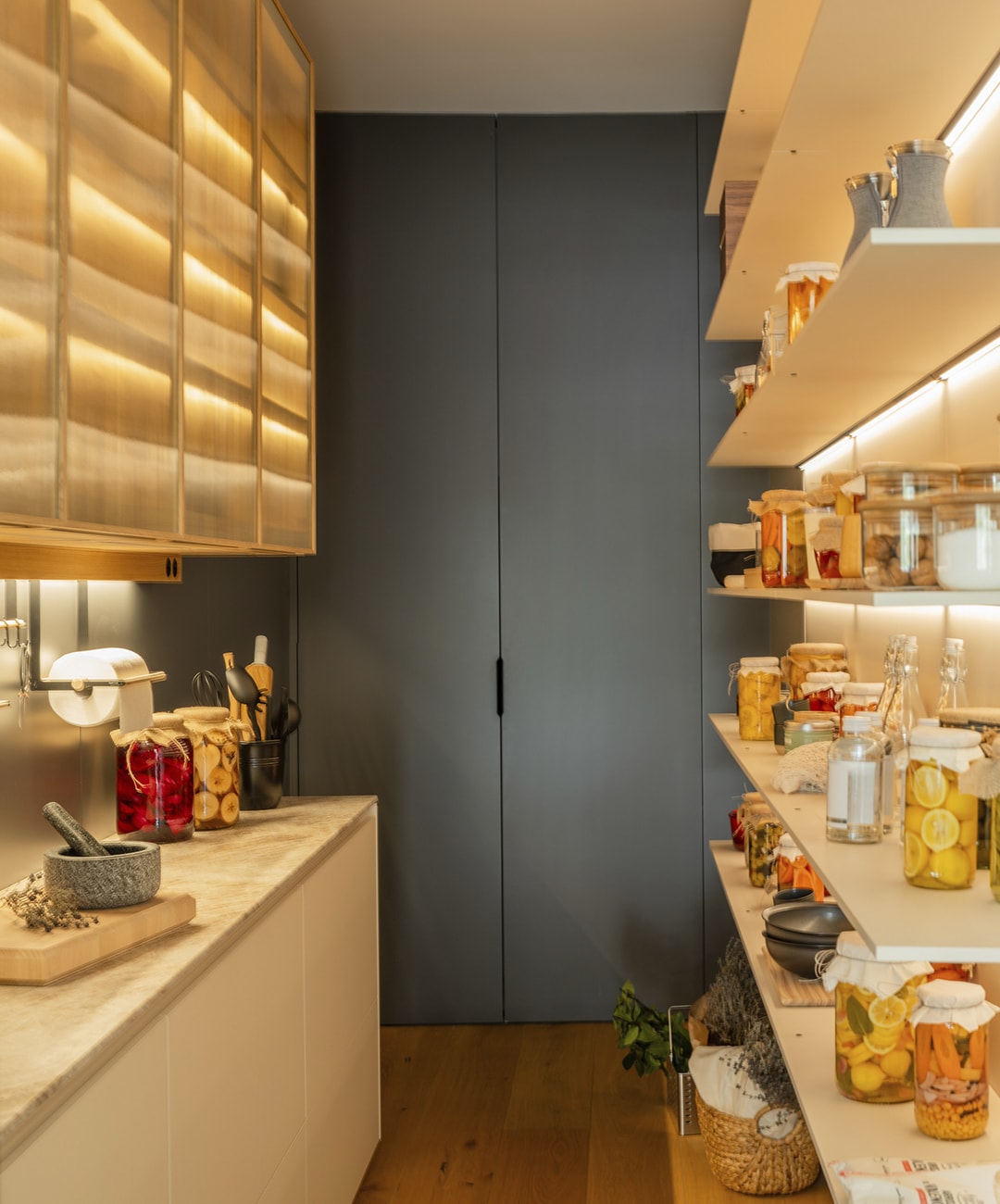 Zona de despensa integrada en la cocina con estanterías y vitrinas de diseño Santos.