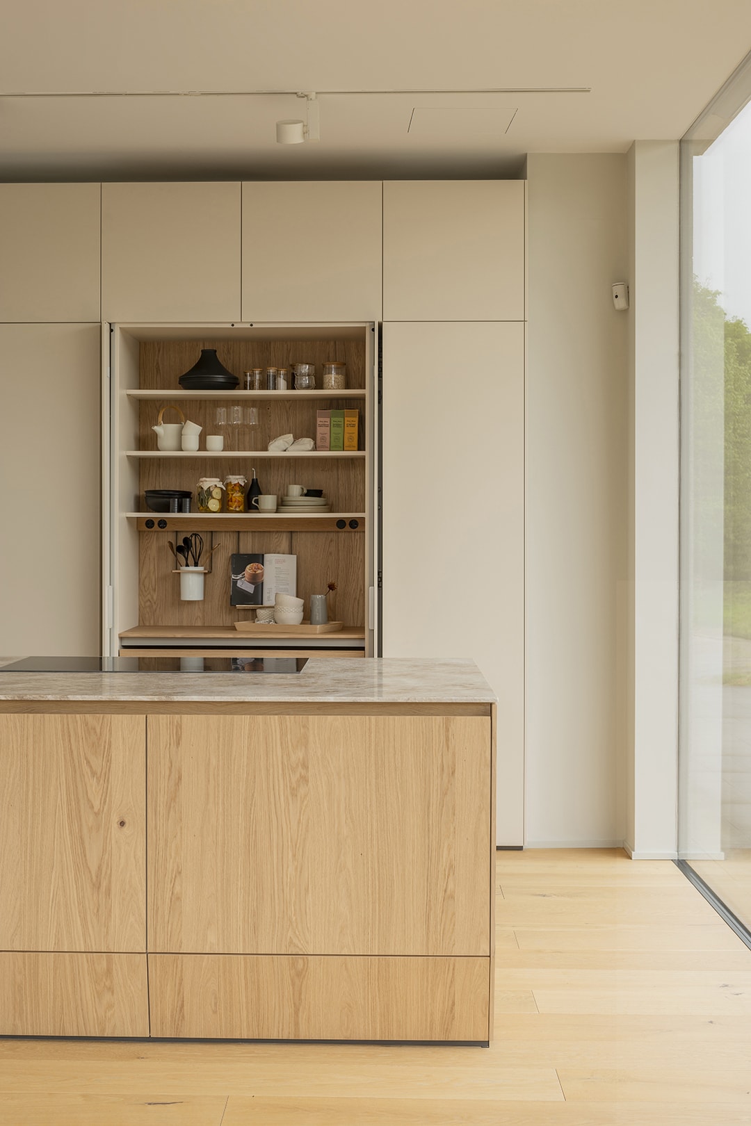 Isla de cocina de madera junto a un armario con puertas escamoteables en el nuevo showroom de Santiago Interiores.