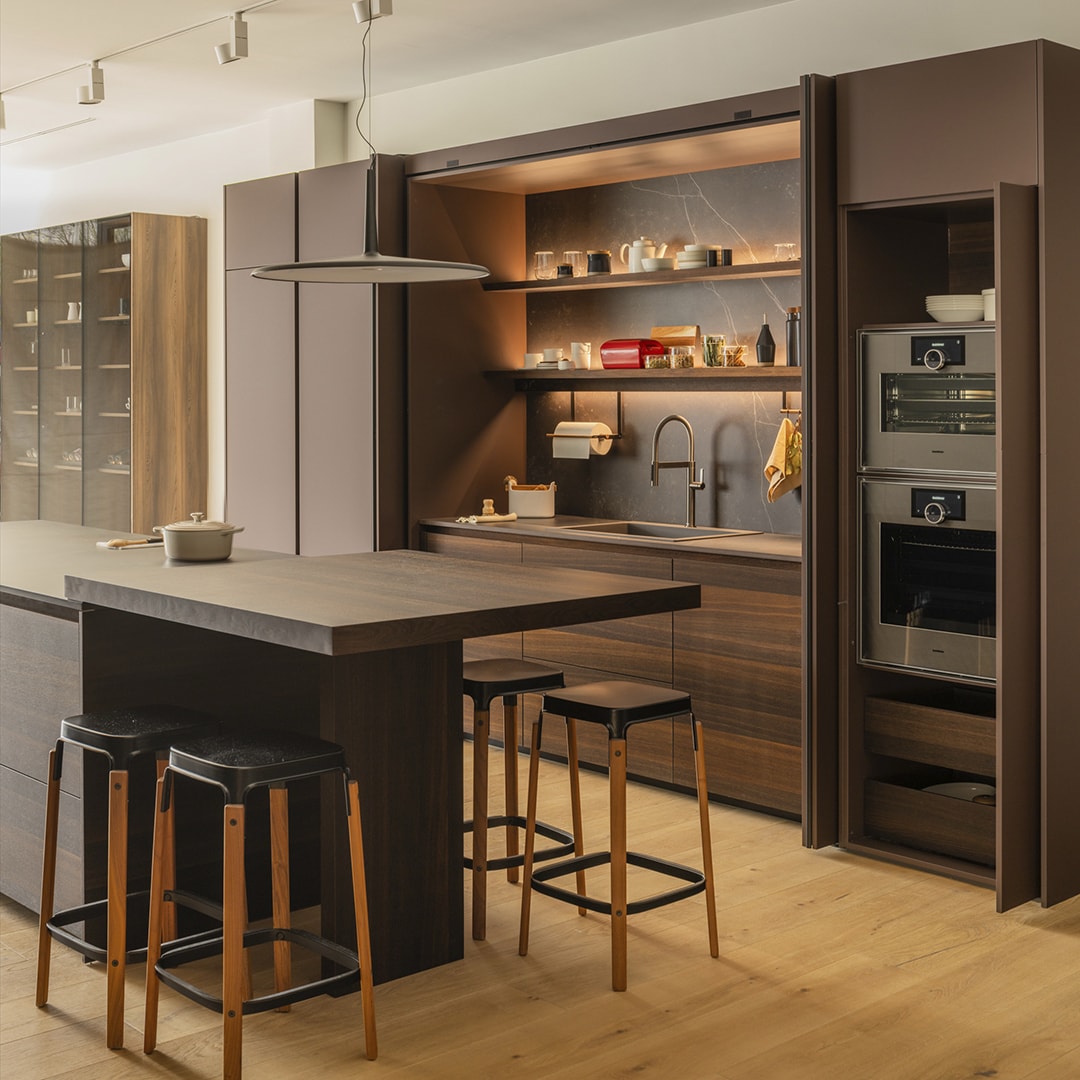 Cocina marrón con acabados en madera e isla con barra en el nuevo showroom de Cocinas Santos en Santiago.