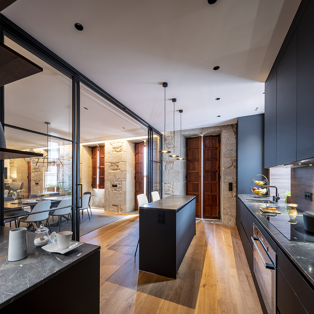 Cocina con cerramiento acristalado e isla diseñada por Santos.