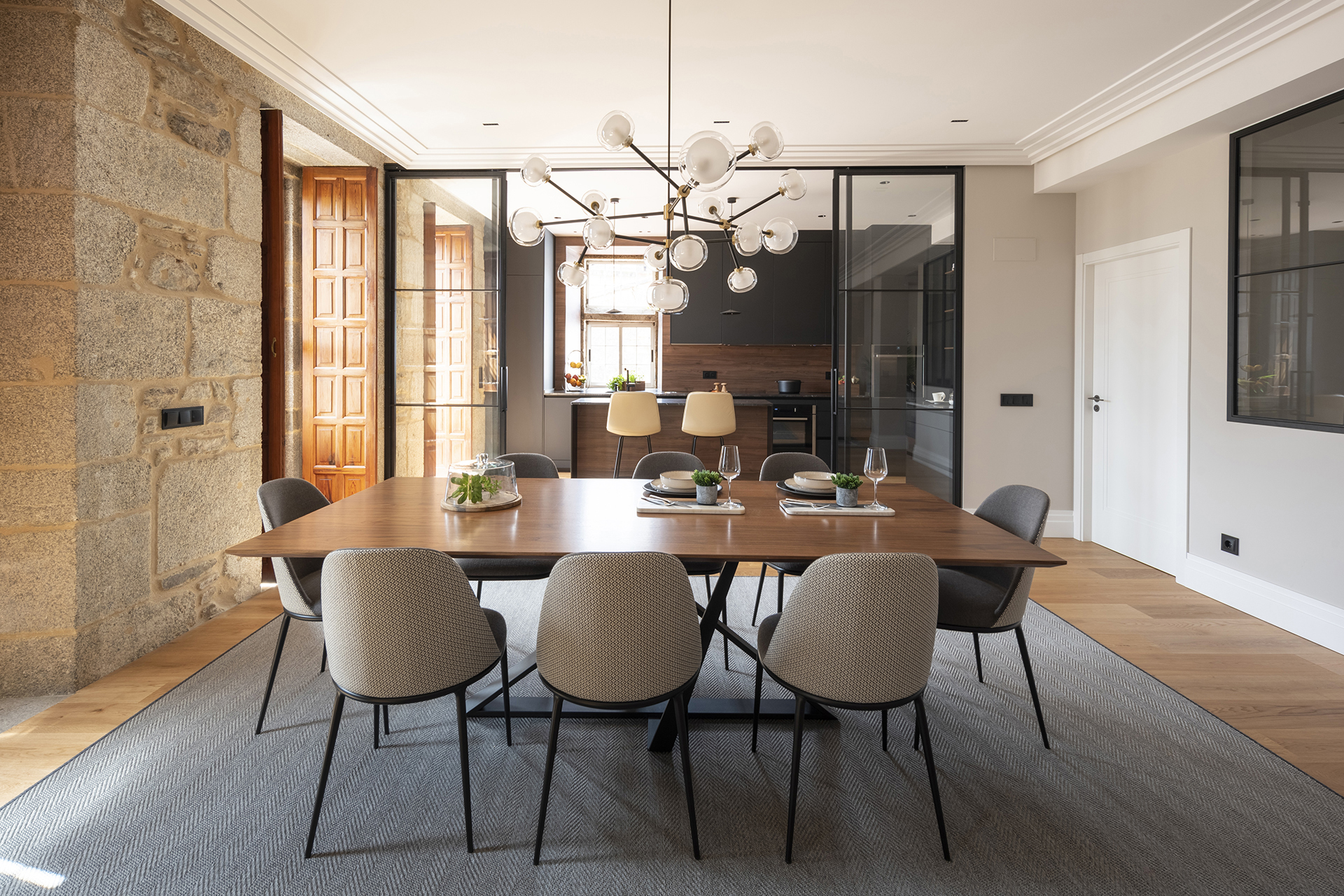 Cocina con cerramiento de cristal abierta al salón diseñada por Santos.
