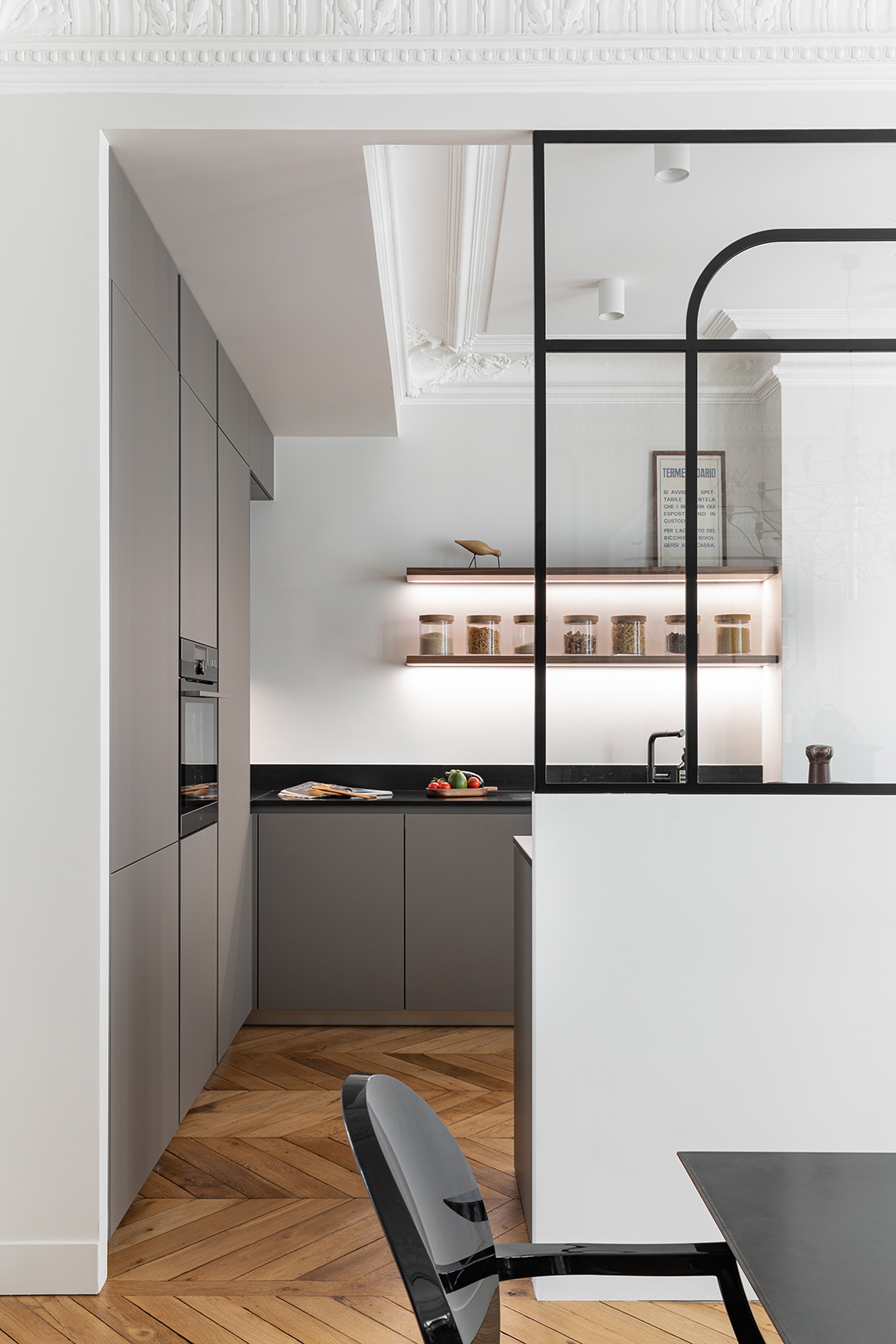 Cocina gris abierta al salón con cerramiento acristalado de Santos.