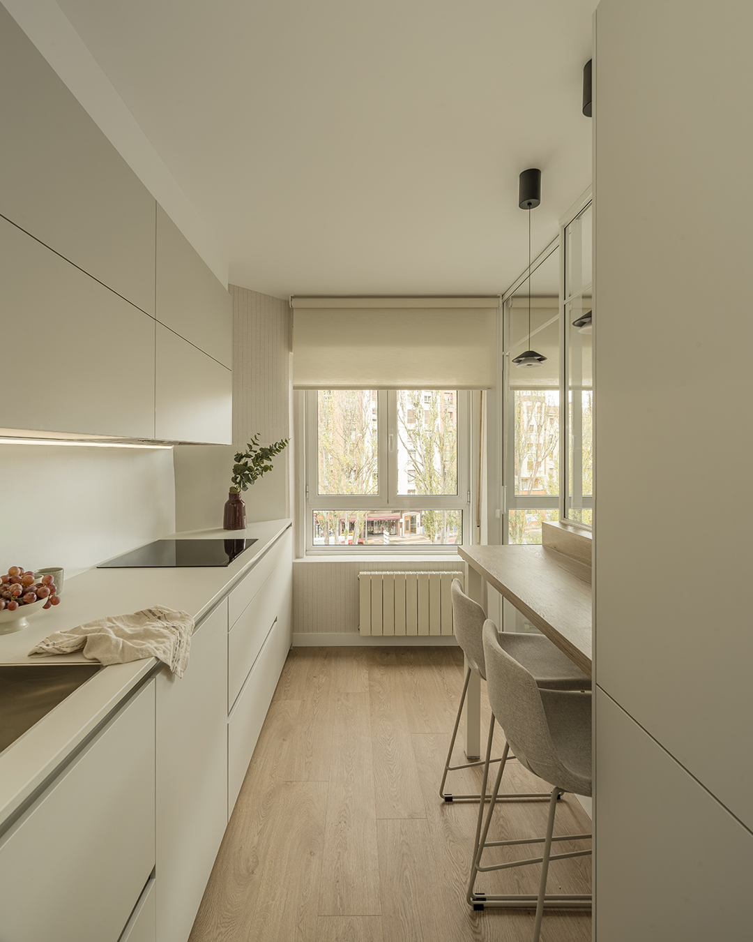 Cocina gris alargada con barra de madera diseñada por Santos.