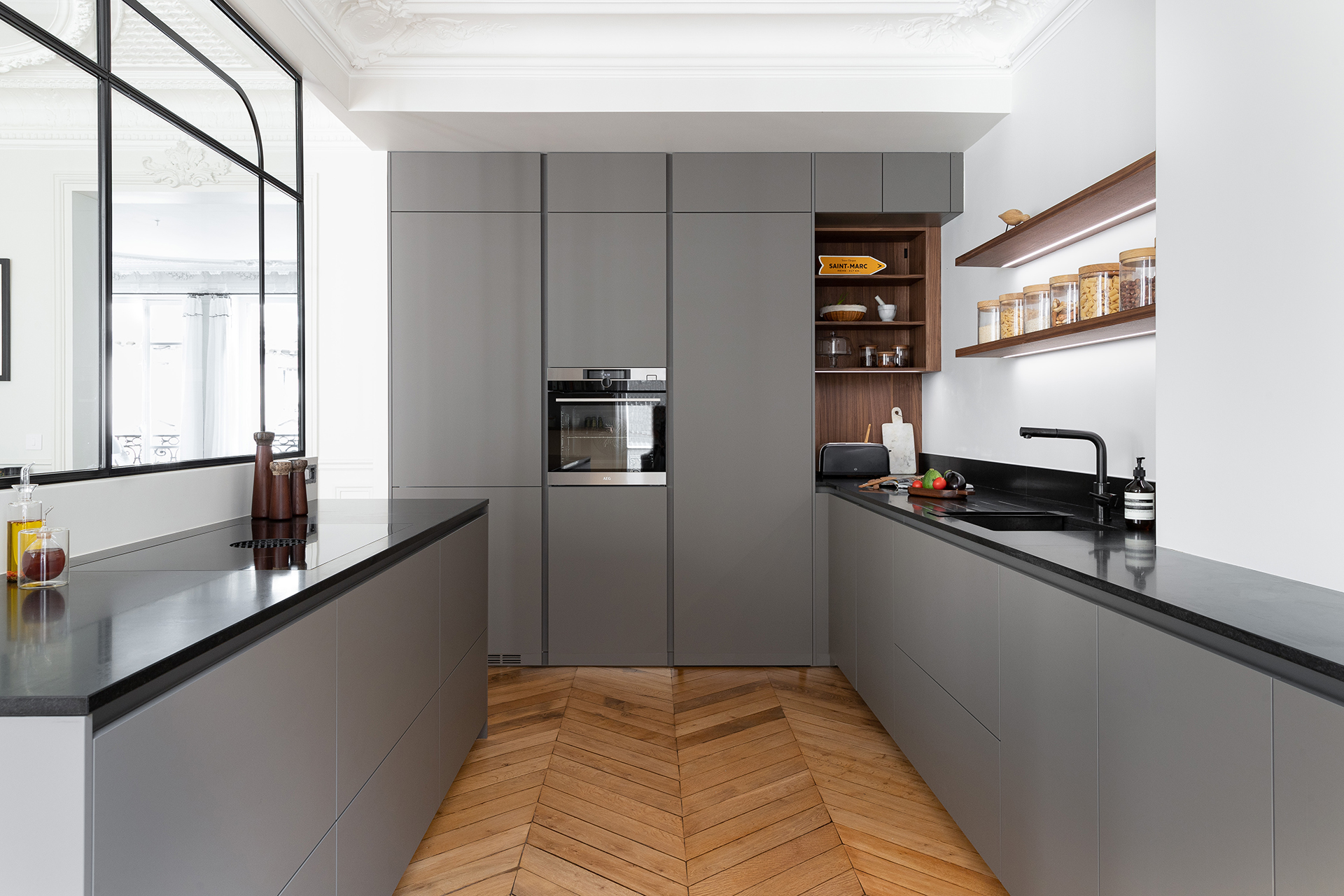 Cocina gris con cerramiento de cristal y acabados en madera de Santos.