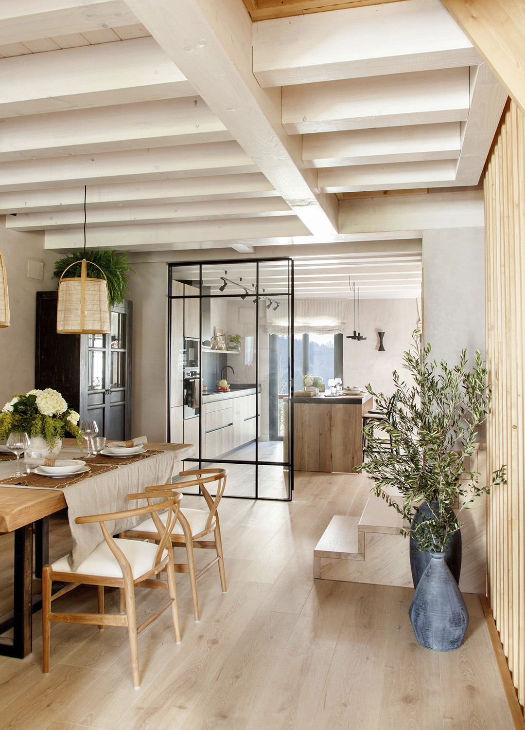 Cocina de madera abierta al salón con cerramiento de cristal de Santos.