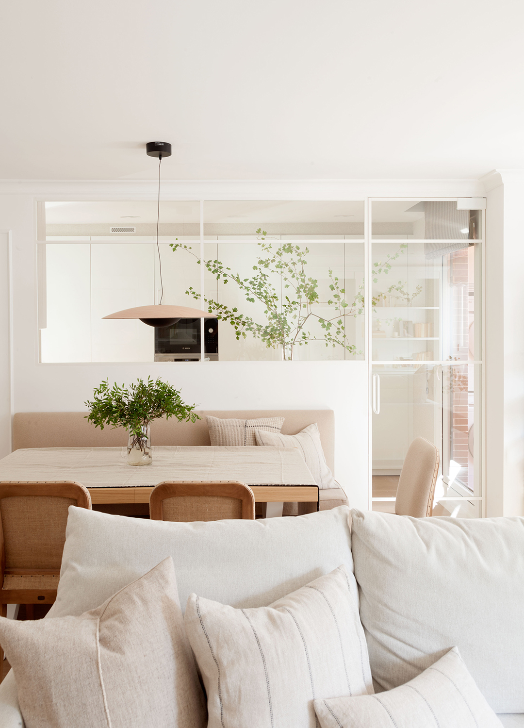 Zona de estar y comedor en una vivienda con cocina Santos con cerramiento de cristal.