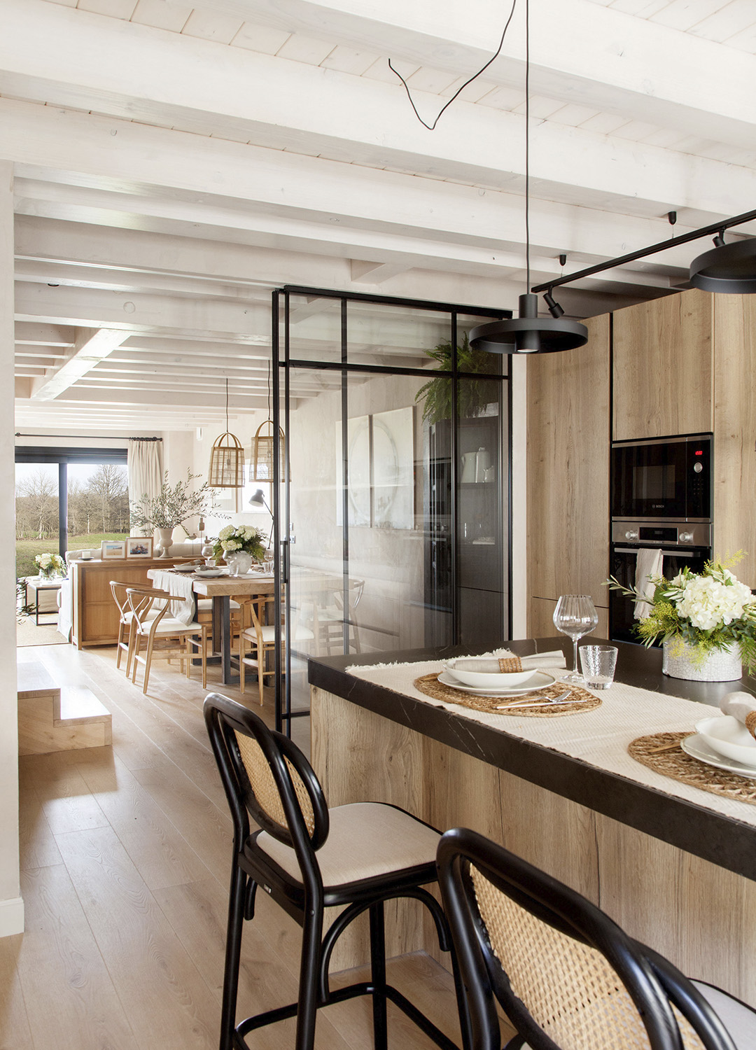Isla central en una cocina de Santos abierta al salón con cerramiento de cristal.