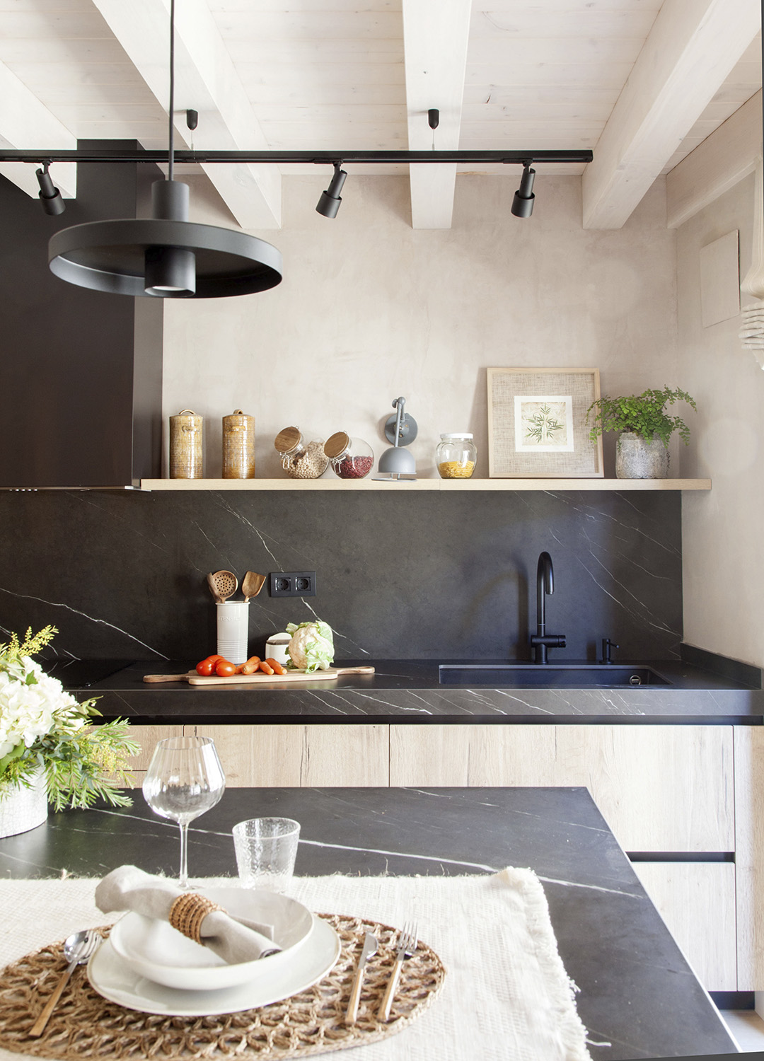 Isla de cocina y encimera en tono negro con acabados en madera diseñada por Santos.